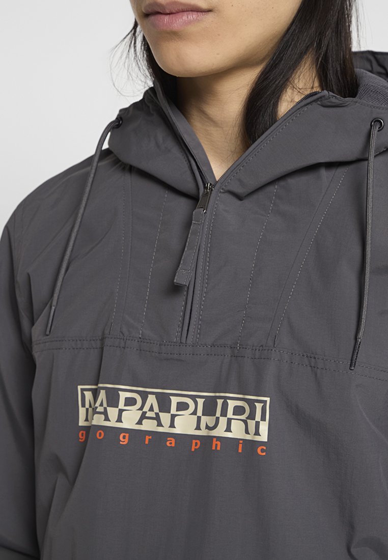 Szary klasyczny bomber z półzamkiem, regulowanym kapturem i wyraźnym logo w kolorze kremowym i pomarańczowym. Wykonany z lekkiego materiału.