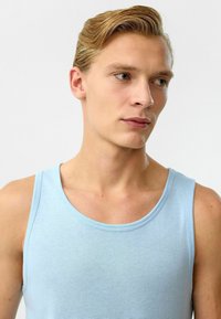 Lichtblauw tanktop gemaakt van katoen, met een ronde halslijn en mouwloos ontwerp. Glad textuur, minimale stikseldetails.