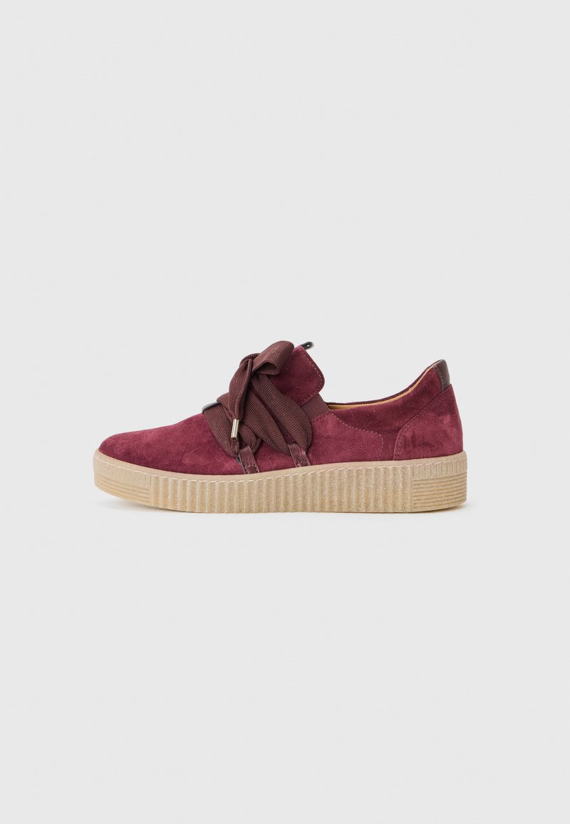 Mørkerød ruskinds sneakers med en afrundet form, der har et bredt brunt båndsnøre, tekstureret beige gummisål og en kontrasterende brun hælaccent.