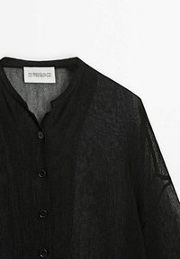 Cardigan noir en maille légère avec encolure ronde et boutons devant, étiquette indiquant Massimo Dutti Limited Edition.