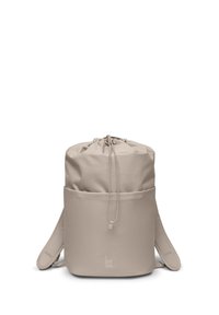 Zaino in tessuto beige con cordoncino, dalla forma arrotondata, dotato di tasca esterna e spallacci regolabili. Caratterizzato da un logo nella parte inferiore.