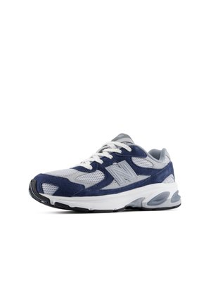 Baskets de sport gris et bleu marine avec lacets blancs et semelle blanche épaisse, en mesh et suède, avec un grand logo "N" sur le côté.