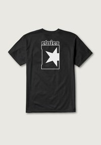 Camiseta negra de manga corta con una gran estrella blanca dentro de un marco rectangular y el texto "etnies" arriba. Textura de tela suave.