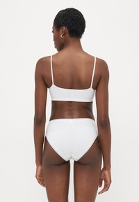 Hvit bralette og høyhånds undertøysett laget av myk stoff, med subtilt blondedekor og justerbare stropper for en behagelig passform.