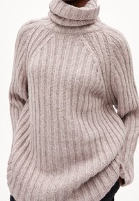 Ljusrosa ribbat stickad tröja med hög polo, långa ärmar och en avslappnad passform. Texturen ser mjuk och mysig ut med subtila detaljer.