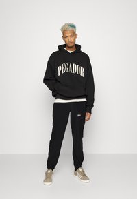 Redefined Rebel ARCHER PANTS UNISEX  - Calças de fato de treino - black