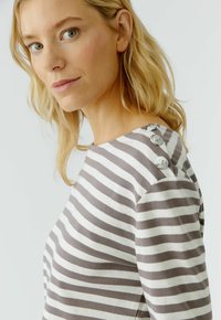 Gestreiftes Langarmshirt aus grauer und cremefarbener Baumwolle, mit dekorativen Knöpfen an der linken Schulter und einem lässigen Schnitt.
