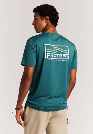 Turkooise surfshirt met korte mouwen, voorzien van een wit logo met oranje en blauwe accenten. Lichtgewicht, ademende stof met een ontspannen pasvorm.