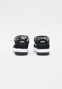 Černé semišové tenisky s bílou mezipodešví a černou podešví. Interiér zdobí černobílý kostkovaný vzor a logo na patě.