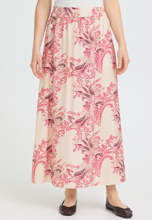 Jupe fluide longueur cheville avec motifs cachemire roses et rouges, taille élastique, portée avec des ballerines noires et un haut blanc.