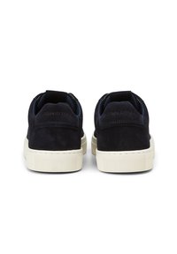 Marineblaue Wildleder-Sneaker mit weißen Gummisohlen, präsentiert im Low-Top-Design und mit einem strukturierten Rückenteil. Markenlogo auf der Ferse geprägt.