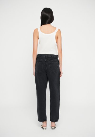 Svarte høy midje jeans med rette ben, med to baklommer og et midjebånd med beltehemper. Kombinert med en hvit tank topp.