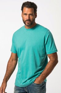 T-shirt colloquia turchese in cotone, con maniche corte e un logo discreto sul petto. Indossato con jeans in denim.