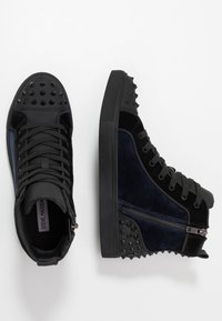 Czarne wysokie trampki wykonane z gładkiej skóry i teksturowanego aksamitu, z nitowanymi akcentami i suwakiem po boku.