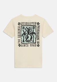 Μπεζ μπλουζάκι με μαύρες αφηρημένες φιγούρες χορού και φοίνικες μέσα σε ένα μπλε τετράγωνο, περιτριγυρισμένο από κείμενο και ανθικά διακοσμητικά στην πλάτη.