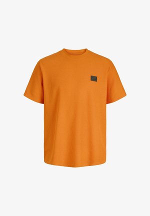 T-shirt orange vif à manches courtes avec texture, col rond, et un petit patch logo carré foncé sur la poitrine gauche.