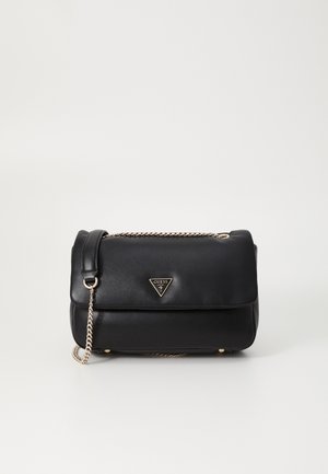 Sac à main en cuir noir avec bandoulière chaîne dorée et logo Guess triangulaire sur le rabat avant sur fond blanc.