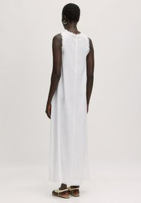Langes, ärmelloses Weißes Kleid aus leichtem Stoff, mit einem ausgefransten Halsausschnitt und Saum, sowie einer lockeren, fließenden Silhouette.