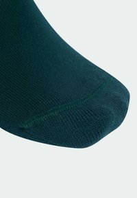 Calzino di cotone verde con una texture liscia, dotato di punta rinforzata e una sottile cucitura a contrasto lungo l'area della punta.