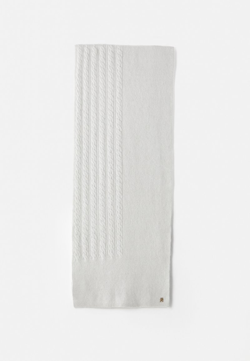 White knitted scarf featuring a ribbed texture on one side and a cable knit pattern on the other, with a small brown brand tag.