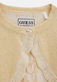 Cardigan a maglia gialla chiara con motivo testurizzato, chiusura con bottone a forma di cuore e etichetta tessuta con "GUESS EST. 1981."
