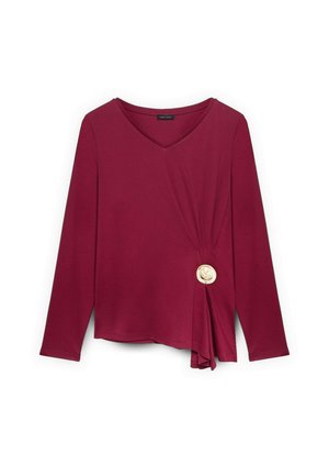 Bordeaux langærmet top med V-hals, med en sidesløjfe og en dekorativ cremefarvet knap. Stoffet ser blødt og strækbart ud.