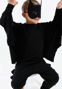 Svart långärmad skjort med vida ärmar och matchande byxor, tillsammans med en svart mask med spetsiga öron och ögonutskärningar.