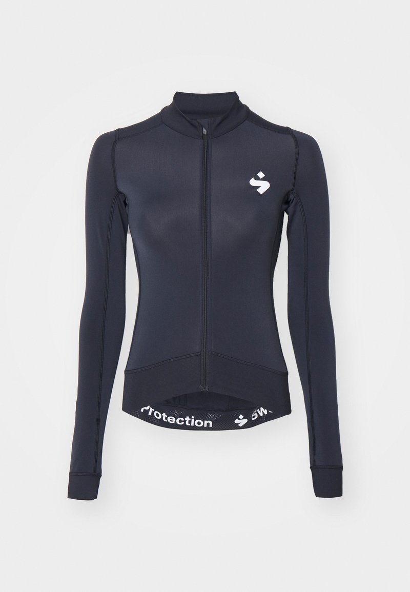 Ναυτικό μπλουζάκι ποδηλασίας με μακριά μανίκια, πλήρη μπροστινό φερμουάρ, γιακά, και λευκό λογότυπο. Διαθέτει ελαστική ζώνη με εκτυπωμένο κείμενο στο στρίφωμα.