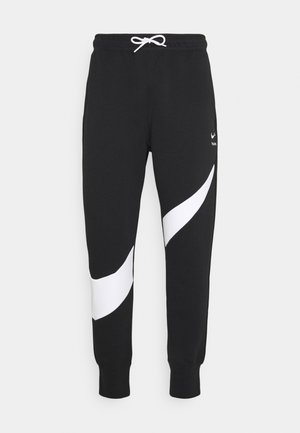 Pantalon de jogging noir avec des bandes blanches courbées sur les jambes, taille élastique avec cordon blanc, et poignets côtelés aux chevilles.