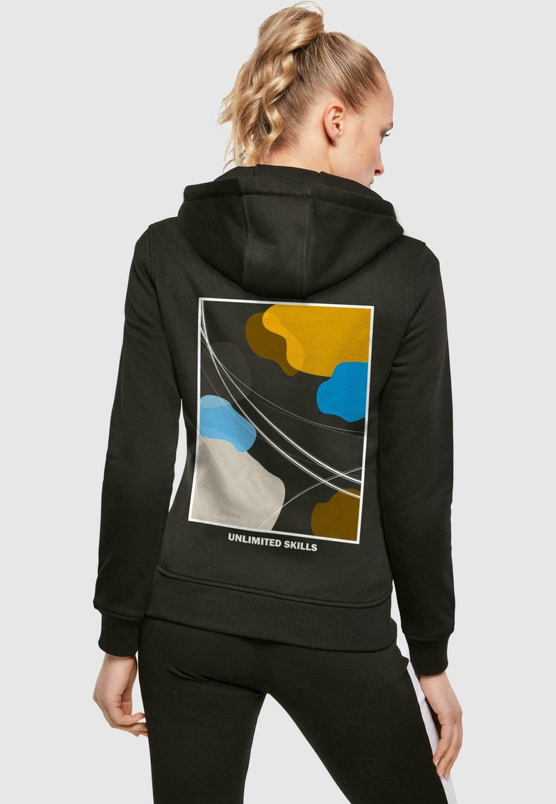 Black hoodie featuring a colorful abstract design on the back with yellow, blue, and gray shapes, and "UNLIMITED SKILLS" text.