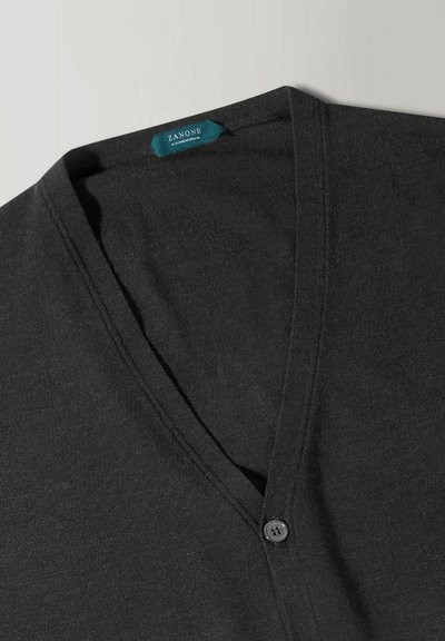 Zwarte v-hals cardigan gemaakt van zachte stof, met een knoopsluiting aan de voorkant en een subtiele textuur. Label zichtbaar binnenin de kraag.