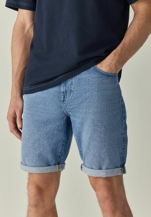 Denim šorts u svijetloplavoj boji, s preklopom na rubu i prednjim džepovima. Tkanina ima blago teksturiranu površinu i ležeran kroj.