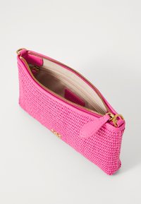 Pieni kirkkaan vaaleanpunainen kudottu clutch-laukku, jossa on kultainen vetskari ja vaaleanbeige kangasvuori, jossa on sisempi vetoketjullinen tasku.
