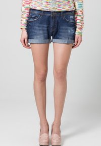 Shorts de mezclilla en azul medio con dobladillos enrollados, que presentan un diseño clásico de cinco bolsillos y un ligero desvanecimiento para un aspecto usado.
