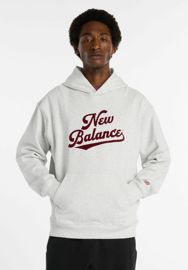 Felpa grigia con un grande logo bordeaux "New Balance". Presenta una tasca frontale, un cappuccio spazioso e polsini a coste per una vestibilità comoda.