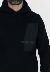 Felpa nera con tasca frontale texture. Presenta una striscia logo tonale e cappuccio, realizzata in un tessuto morbido. Design semplice e moderno.