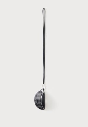Borsetta nera semicircolare da polso con motivo geometrico e zip, fissata a una lunga e sottile cinghia progettata per essere portata al polso.