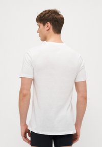 Weißes Baumwoll-T-Shirt mit klassischem Rundhalsausschnitt und kurzen Ärmeln, das eine glatte Textur und ein einfaches, ungeschmücktes Design aufweist.