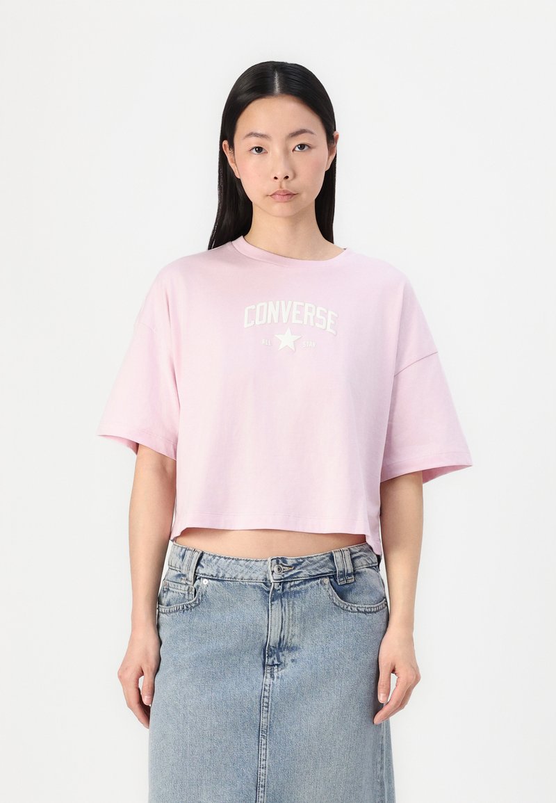 Rosa kortermet t-skjorte laget av bomull. Har hvit tekstdesign og stjernelogo. Bær sammen med et lys blått denimskjørt.