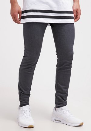 Jeans ajustados grises con una textura suave, que presentan una cintura de altura media y un diseño clásico de cinco bolsillos, combinados con zapatillas blancas.