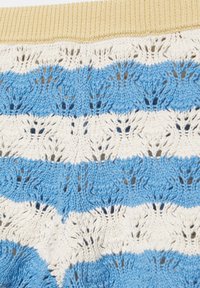 Tissu tricoté avec des motifs de dentelle bleus et blancs alternés et une bordure côtelée jaune en haut.
