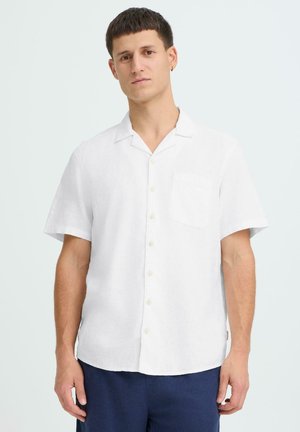 Chemise en lin blanc à manches courtes avec col, poche poitrine unique et devant à boutons. Texture lisse, coupe décontractée et design simple.