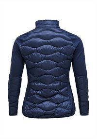 Marineblauwe jas met een gewatteerde, gevoerde achterkant en soepele mouwen. Kenmerkt zich door een hoge kraag en een gestructureerd golvenpatroon over de achterkant.