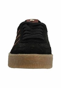 Black suede sneaker with black laces, tan rubber sole, and brown accents. Features three brown stripes along the side and a logo on the tongue.