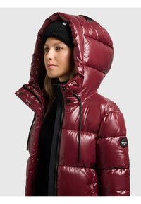 Chaqueta acolchada burdeos con acabado brillante, capucha grande, detalles en negro y cordones ajustables. Incluye un parche con el logo en la manga.