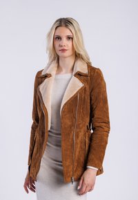 Veste en daim marron avec un col en fausse fourrure couleur beige, fermeture éclair à l'avant et poches latérales, présentant une coupe ajustée et une texture lisse.