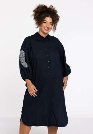 Navyblaues Kleid aus Stoff mit durchgehender Knopfleiste, 3/4-Puffärmeln und einem dekorativen gestickten Muster auf dem linken Ärmel.