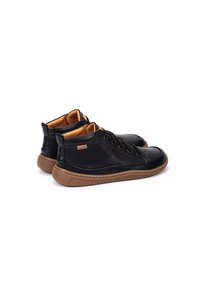 Zapatos altos de cuero negro con acentos en color marrón y suela de goma. Las características incluyen puntera redonda, sistema de cordones en la parte delantera y detalles de costura en los laterales.
