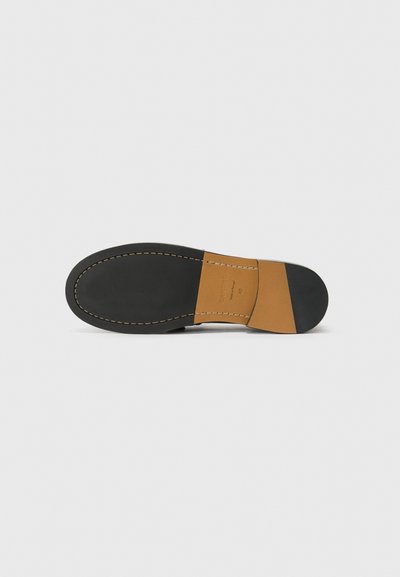 Suela de zapato de cuero negro con un acento en tono marrón claro, que presenta un acabado suave, bordes cosidos y una forma redondeada. Suela de goma texturizada para un mejor agarre.