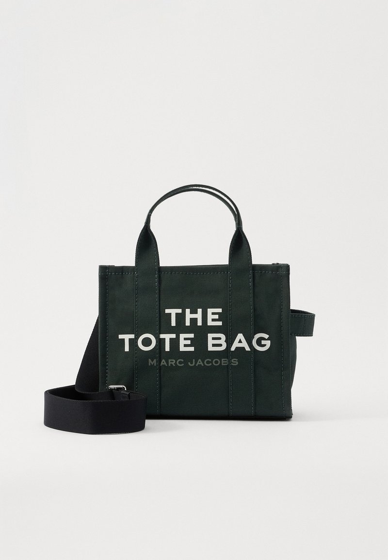 Sort rektangulær tote-taske med dobbelte håndtag og aftagelig skulderrem, hvid tekst "THE TOTE BAG MARC JACOBS" i midten på fronten.